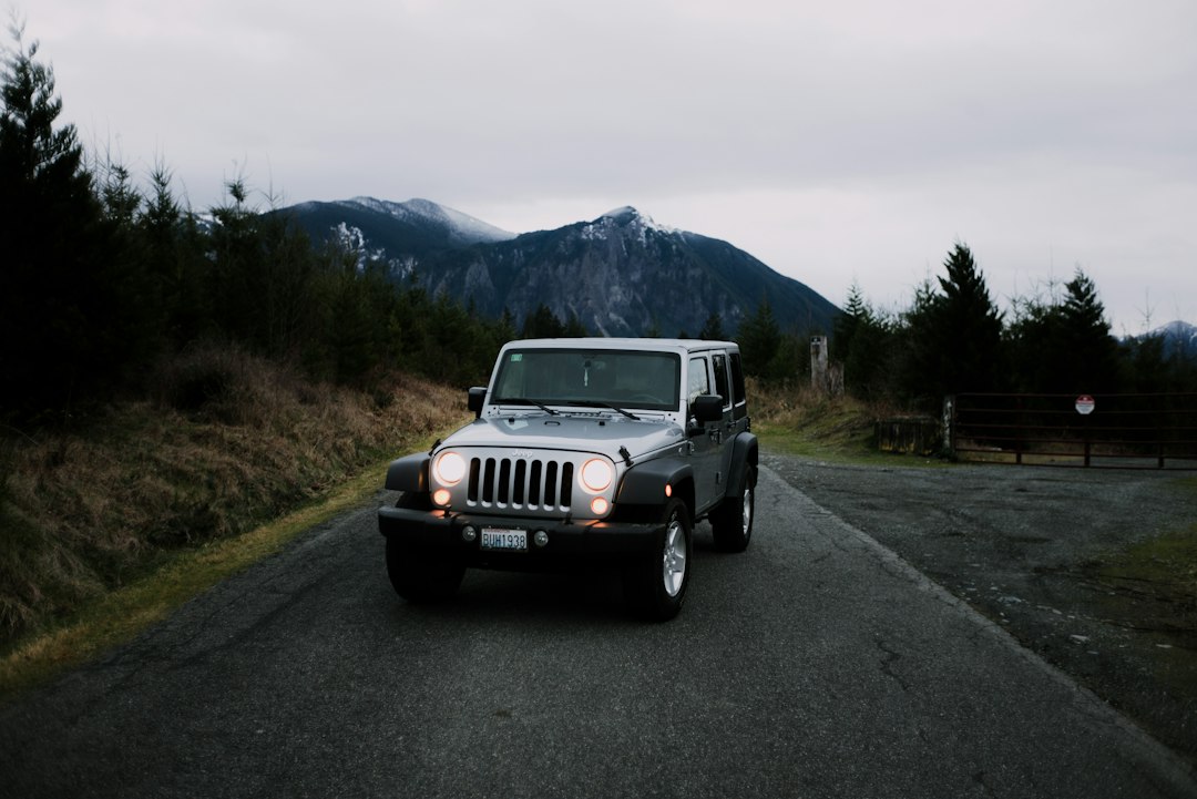 White 4x4 jeep on a road with green hills and mountains White 4x4 jeep on a road with green hills and mountains